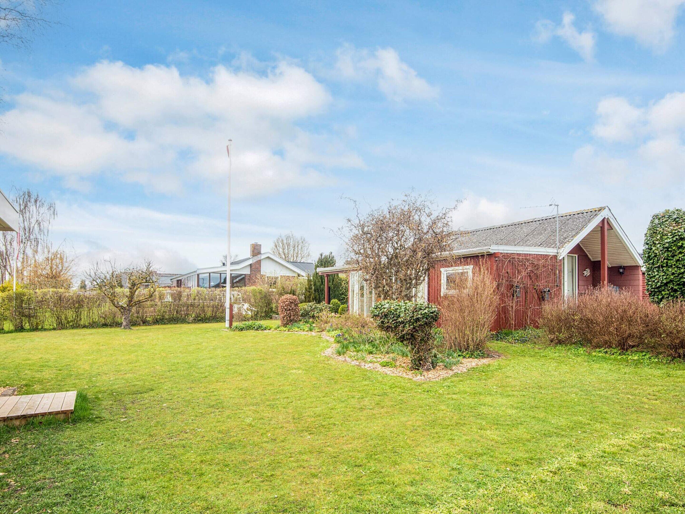 A residential property with a well-maintained lawn, a red brick house, and a clear sky.