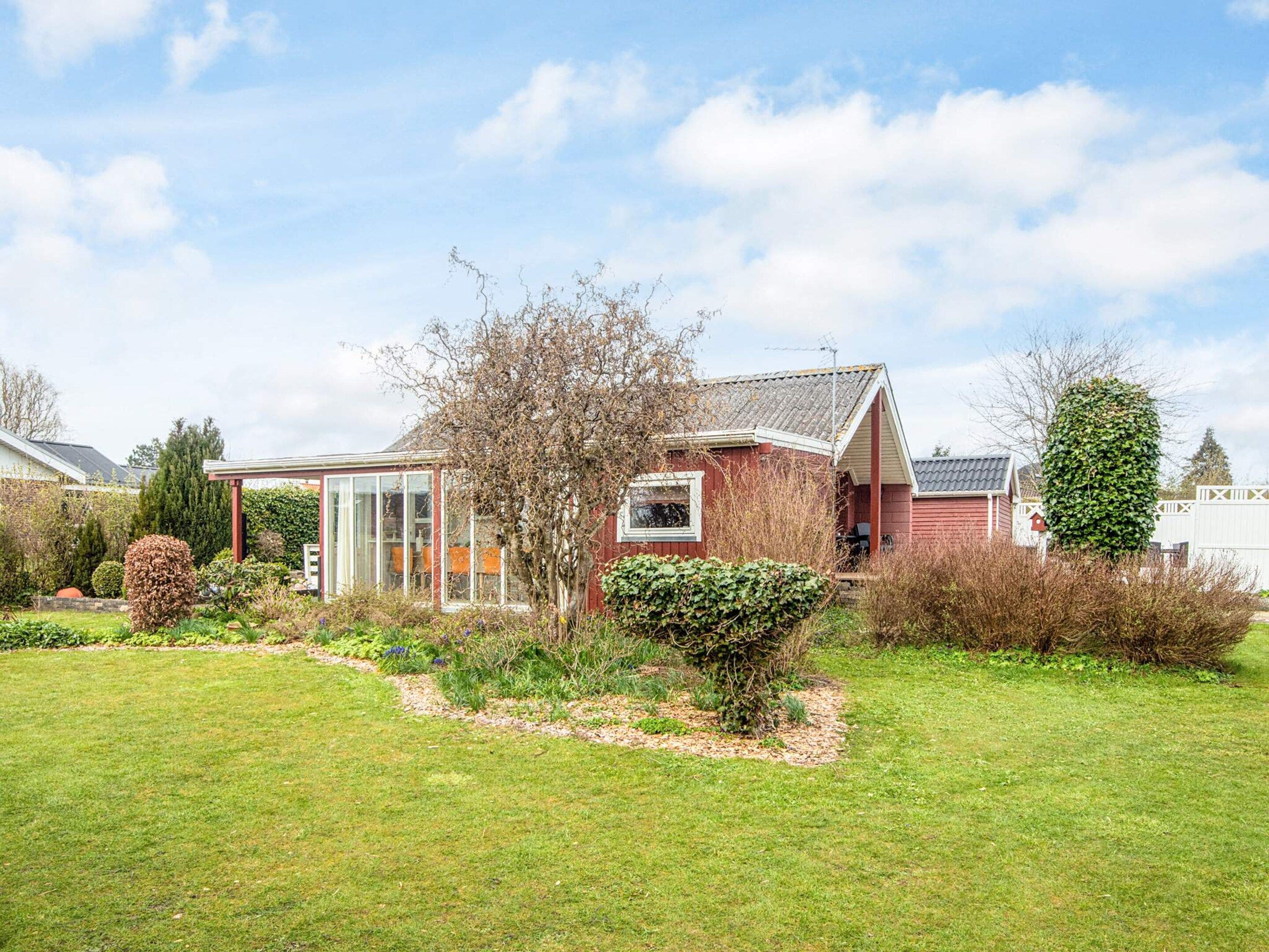 A residential property with a red house, a conservatory, and a well-maintained garden.