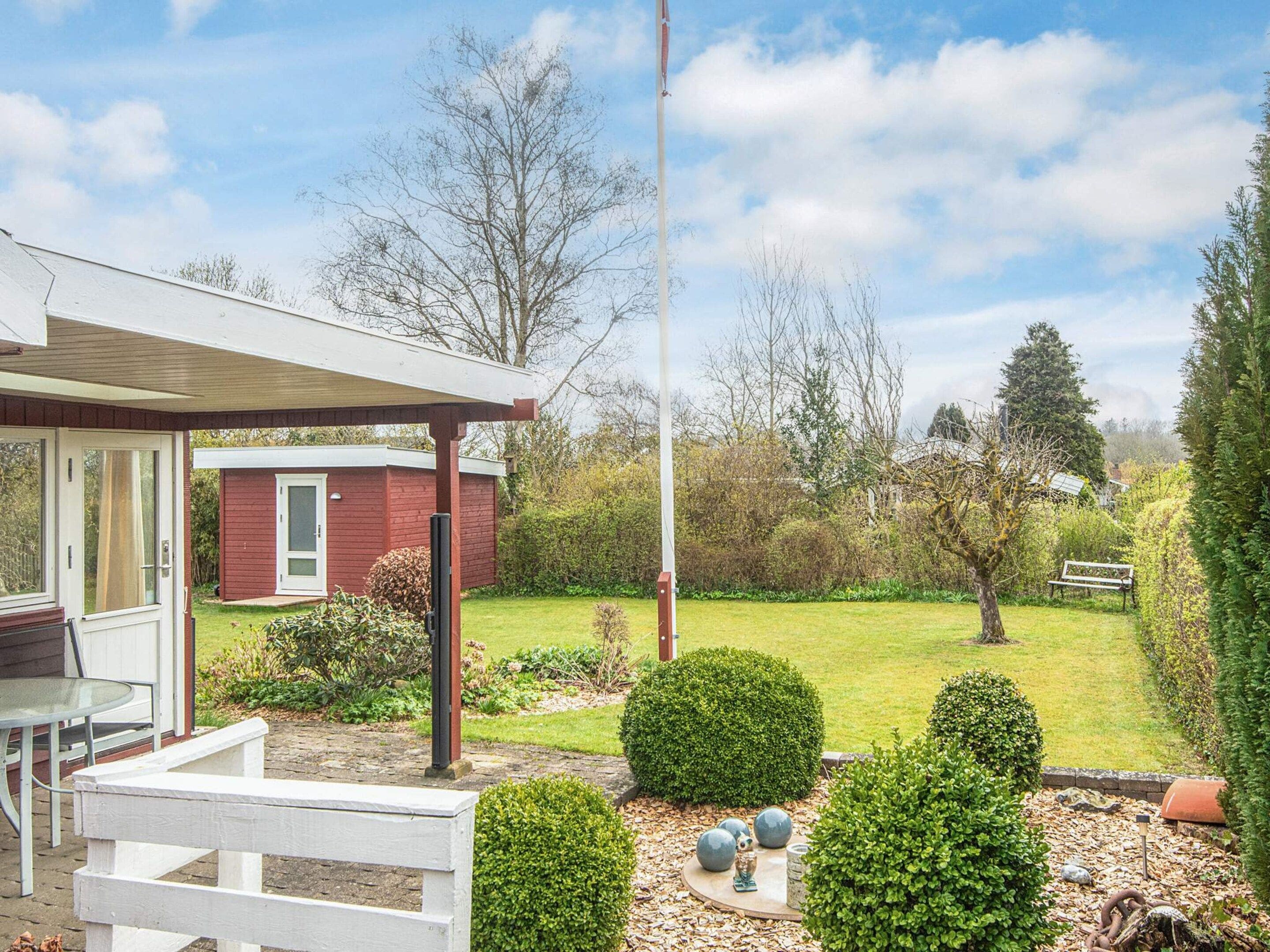A residential property with a covered patio, a small shed, and a well-maintained garden with hedges and a lawn.
