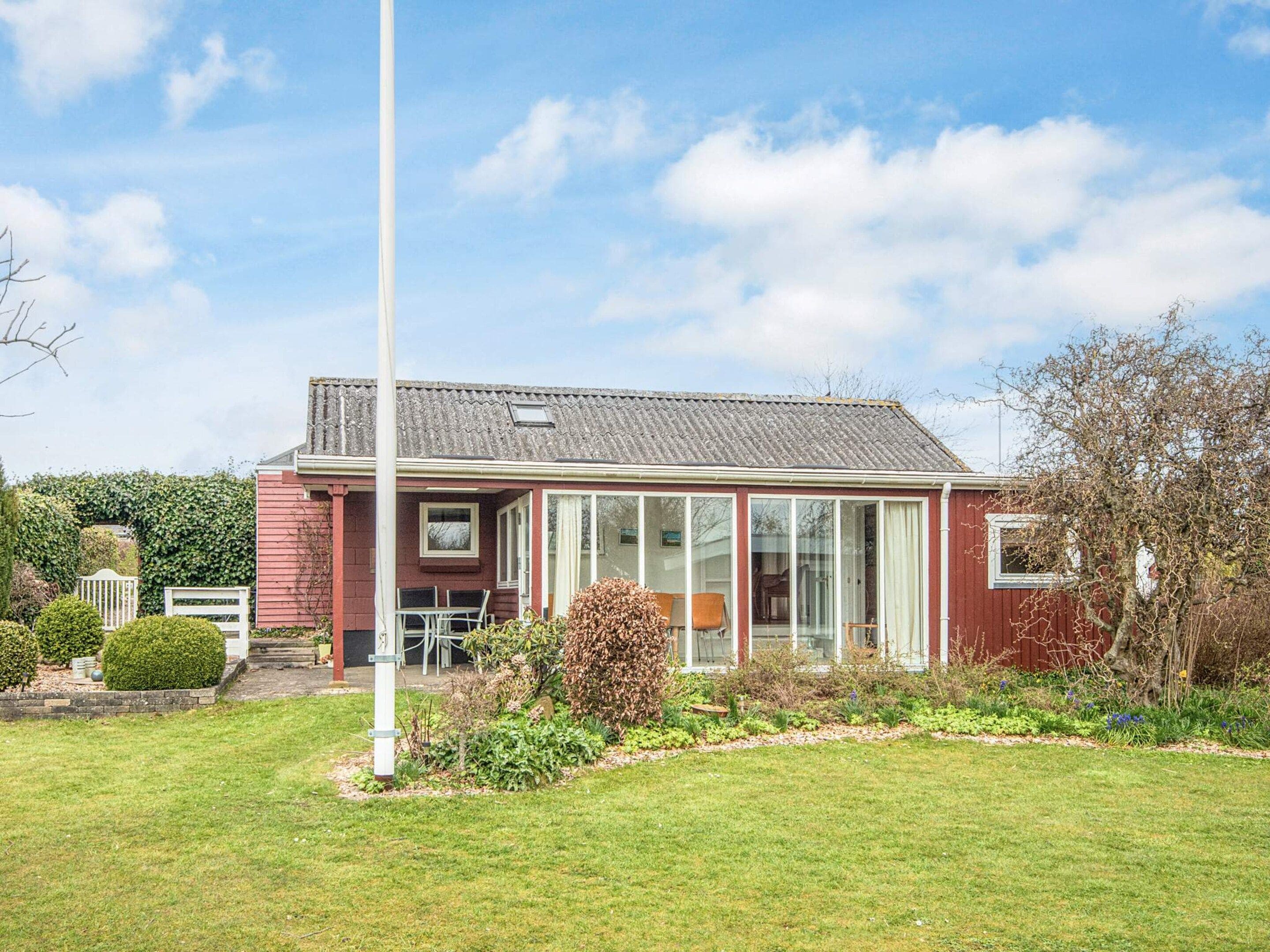 A red brick house with a large glass door and windows, surrounded by a well-maintained garden.
