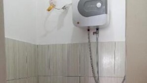 Um banheiro pequeno com vaso sanitário, chuveiro e secador de mãos fixado na parede.