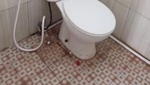 A small bathroom with a toilet, a visible pipe, and a patterned floor. - OYO Life 92543 Ratu Sakti Residence Syariah (Semarang)