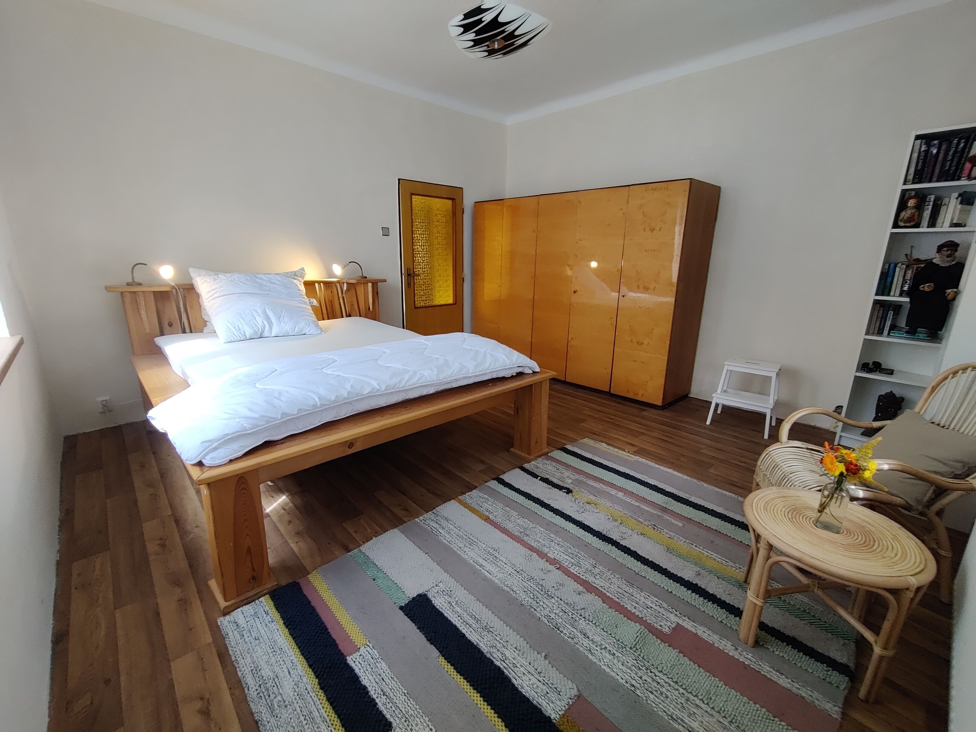 Une chambre à coucher comprenant un lit, des tables de chevet, une armoire, une chaise et une bibliothèque.