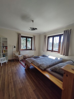 Ein Schlafzimmer mit einem Bett, einem Sessel, einem Bücherregal und einem Fenster.