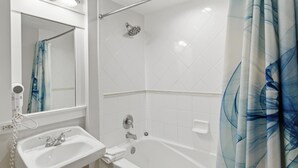 Ein Badezimmer mit Waschbecken, Spiegel, Dusche und Handtuchhalter.