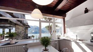 A modern kitchen with a large window overlooking a mountainous landscape. - Villa Meraviglia  (Olgiasca)