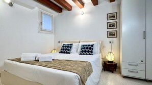 Ein Schlafzimmer mit Bett, Nachttischlampe, Kleiderschrank und Fenster.