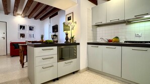 Eine Küche mit weißen Schränken, einem eingebauten Backofen und einem Essbereich mit einem roten Sofa.