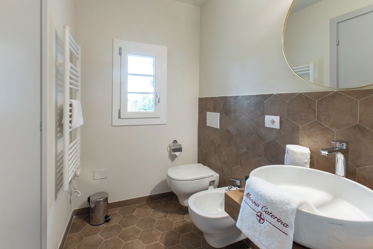 Un baño con inodoro, bidé y un lavabo grande con espejo arriba.