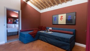 Una habitación con un sofá sectional azul, techo de madera y una pared decorada con arte abstracto.