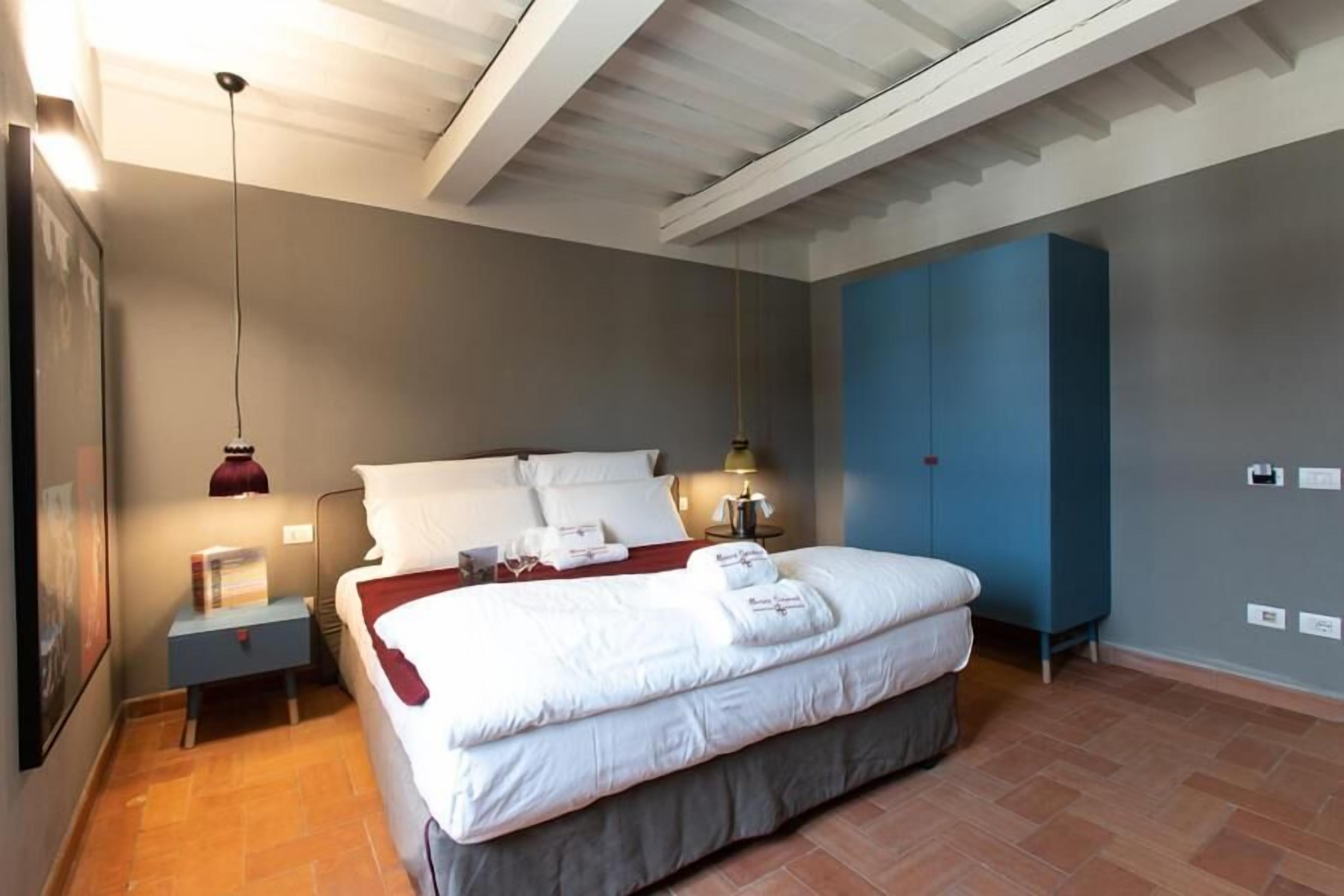 A bedroom with a bed, bedside tables, a wardrobe, and a ceiling with exposed beams.