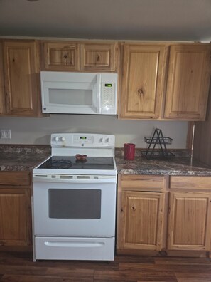 A kitchen with wooden cabinets, a microwave, an oven, and a granite countertop. - Charming 3-bedroom house in Ava, NY. (Ava)