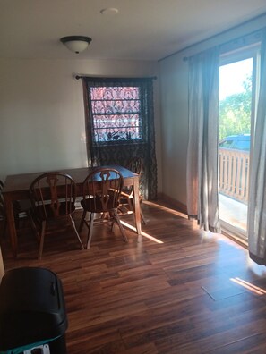 A dining area with a table and chairs, a window with patterned curtains, and a view of the outside. - Charming 3-bedroom house in Ava, NY. (Ava)