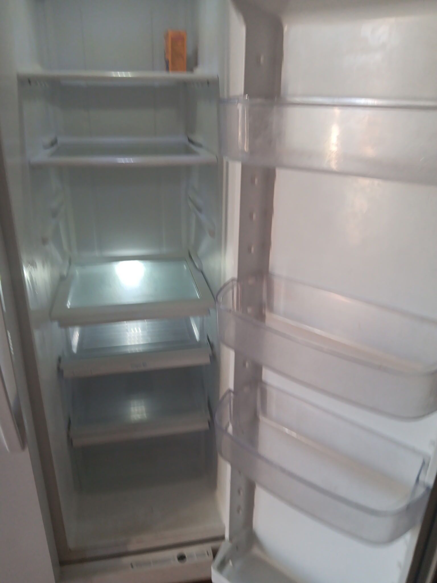 Un refrigerador buit amb diverses prestatgeries i un objecte petit taronja a la prestatgeria superior.