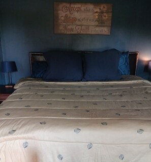 Een slaapkamer met een bed, een bord aan de muur en een nachtkastje met een lamp.