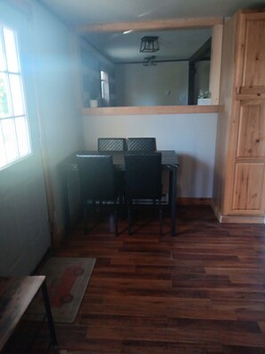 A room with a wooden floor, a dining table with chairs, a window, and a wooden cabinet. - Charming 3-bedroom house in Ava, NY. (Ava)