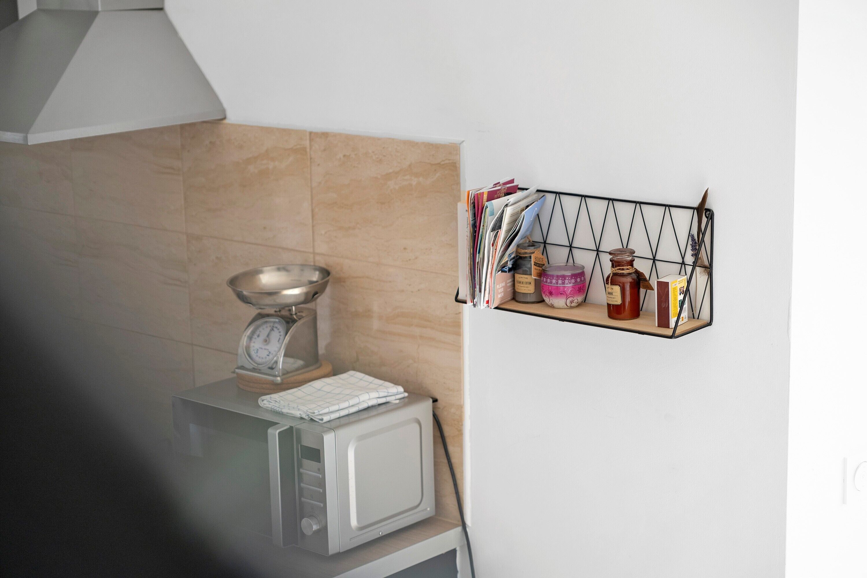 A kitchen with a microwave, a scale, and a spice rack.