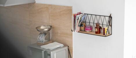 A kitchen with a microwave, a scale, and a spice rack.