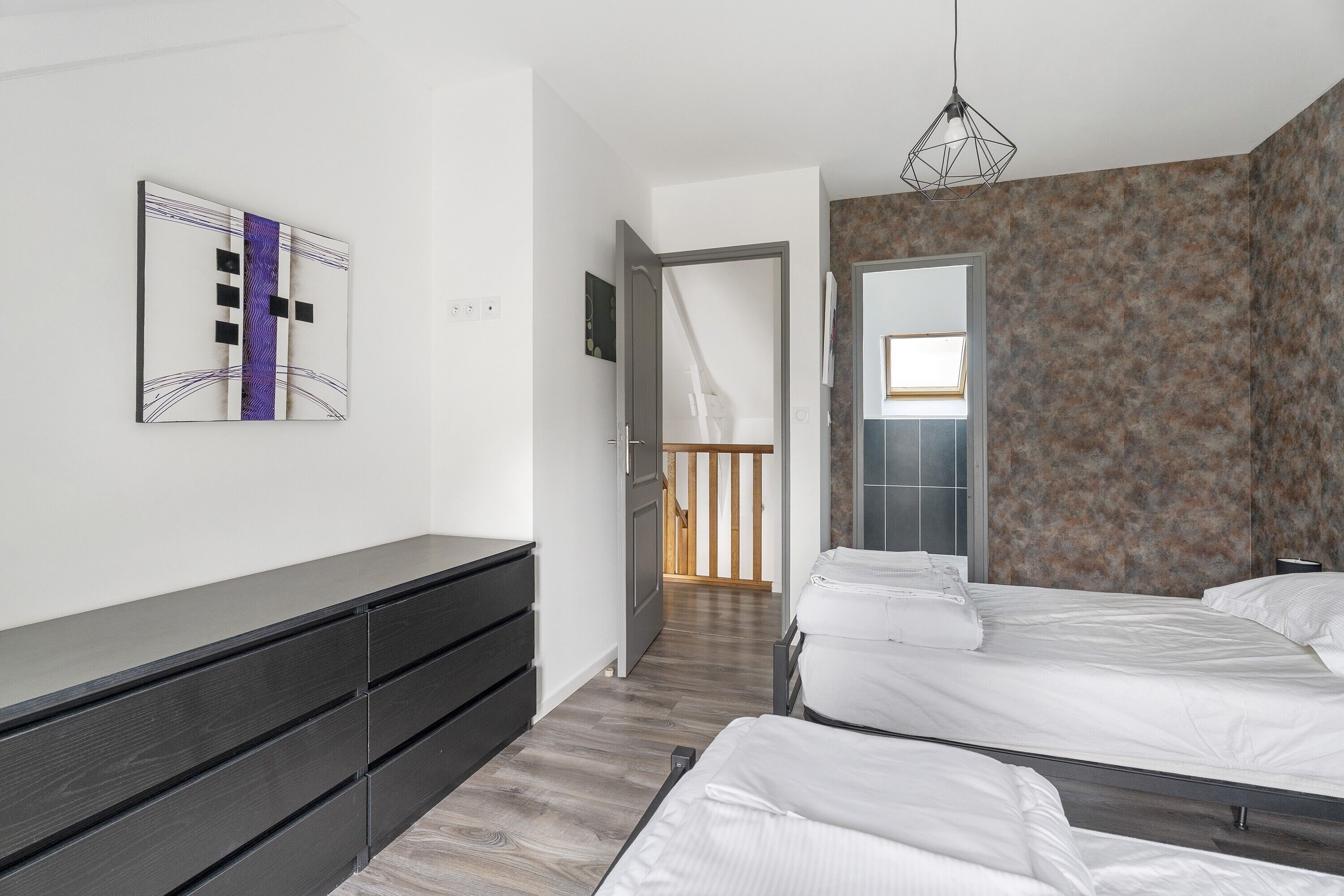A modern bedroom with a bed, a dresser, and a wall-mounted artwork.