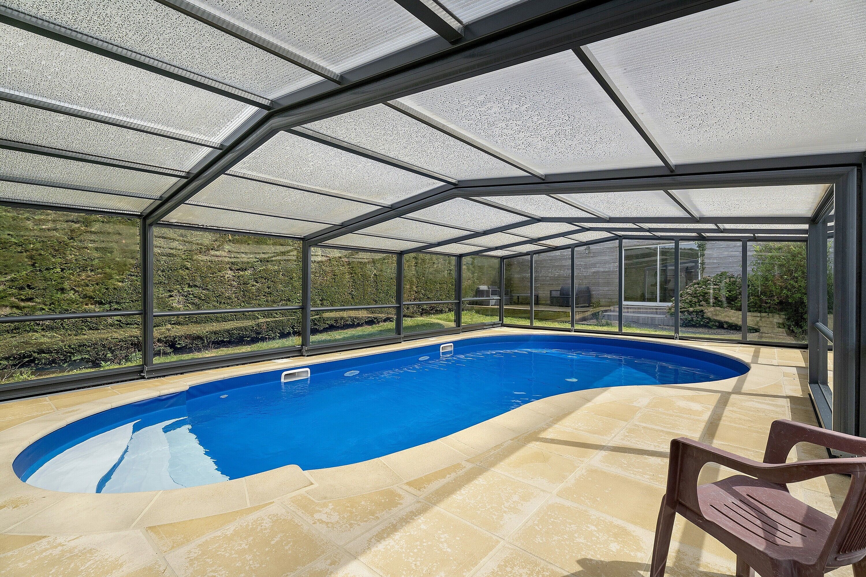 Une piscine dotée d’une enceinte en verre, entourée d’un espace patio.
