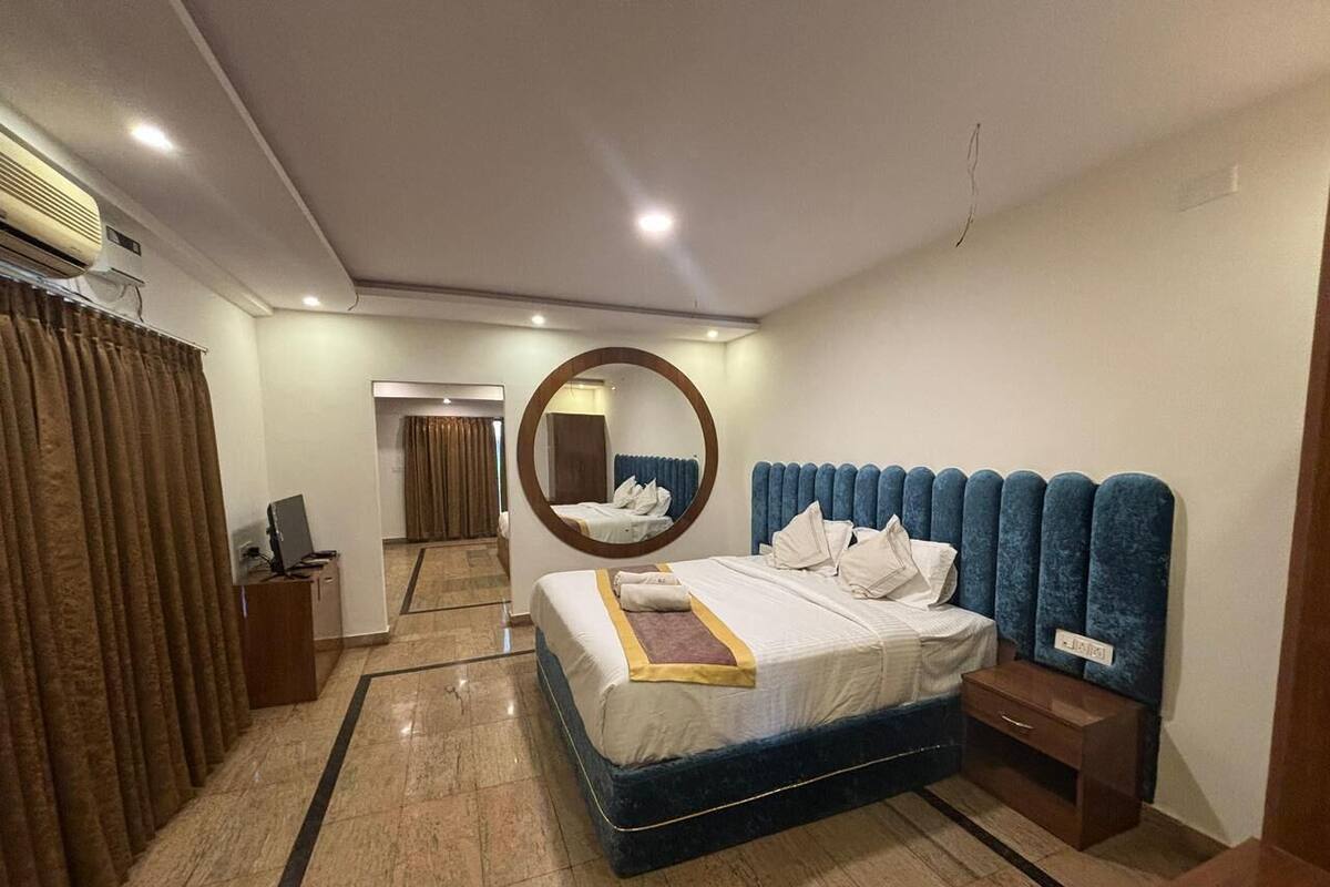 Una habitación de hotel con cama, mesita de noche, espejo y vista al pasillo.