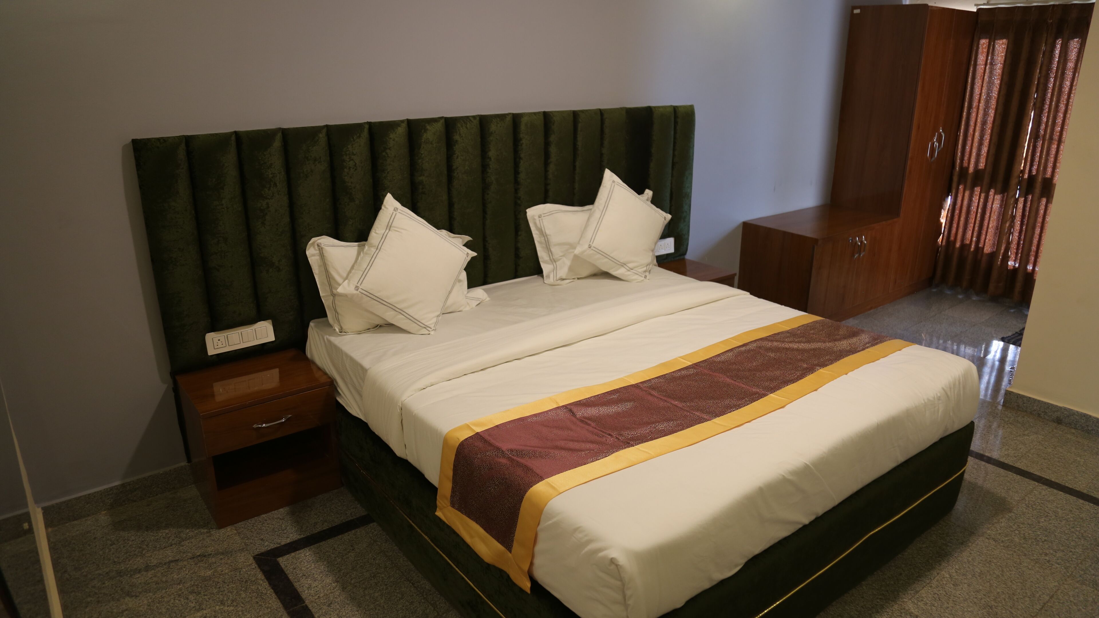 A hotel room with a bed, a nightstand, a wooden wardrobe, and a green headboard.