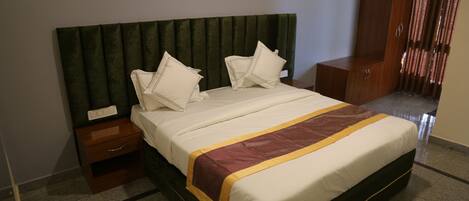 A hotel room with a bed, a nightstand, a wooden wardrobe, and a green headboard.