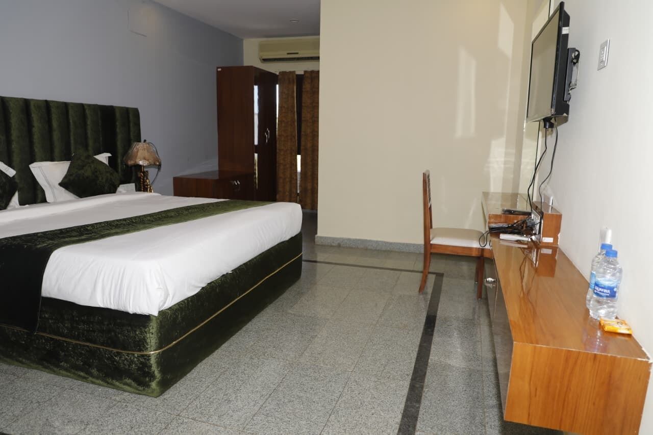 Ein Hotelzimmer mit Bett, Schreibtisch, Stuhl, Fernseher und Kleiderschrank.