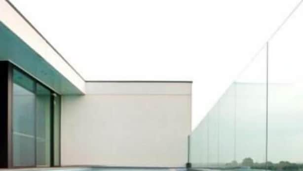 A rooftop swimming pool with a clear view of the sky and a modern building in the background.