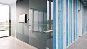 A hotel corridor with glass doors, a flat-screen TV, and a view of the city.