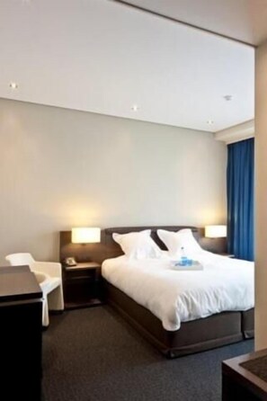 A hotel room with a bed, bedside tables, a desk, and a chair. - Blue Woods Hotel (Deerlijk)