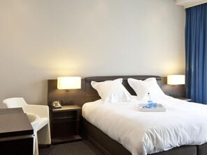 A hotel room with a bed, bedside tables, a desk, and a chair. - Blue Woods Hotel (Deerlijk)