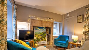 A living room with a fireplace, a television, and a blue armchair. - East Bank (Matlock)