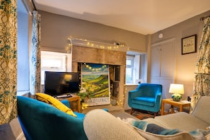 A living room with a fireplace, a television, and a blue armchair. - East Bank (Matlock)