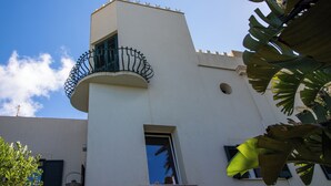Ein Gebäude mit weißer Fassade, einem Balkon mit schmiedeeisernem Geländer und einem kleinen Fenster.