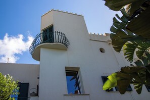A building with a white facade, a balcony with a wrought iron railing, and a small window.