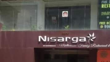 A building with a sign reading 'Nisarga' and a staircase leading to the entrance.