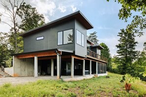 Une maison moderne à deux étages, dotée d’un porche abrité, de grandes fenêtres et d’un balcon.