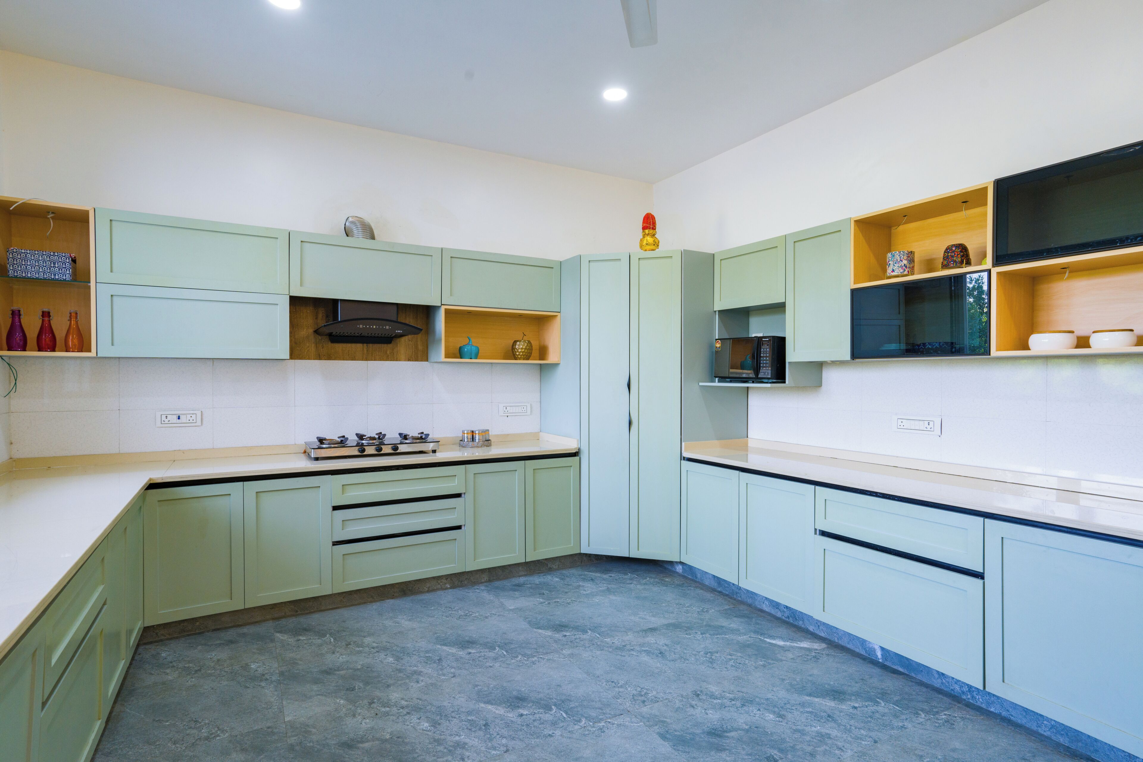 A kitchen with green cabinets, a stove, and a microwave.