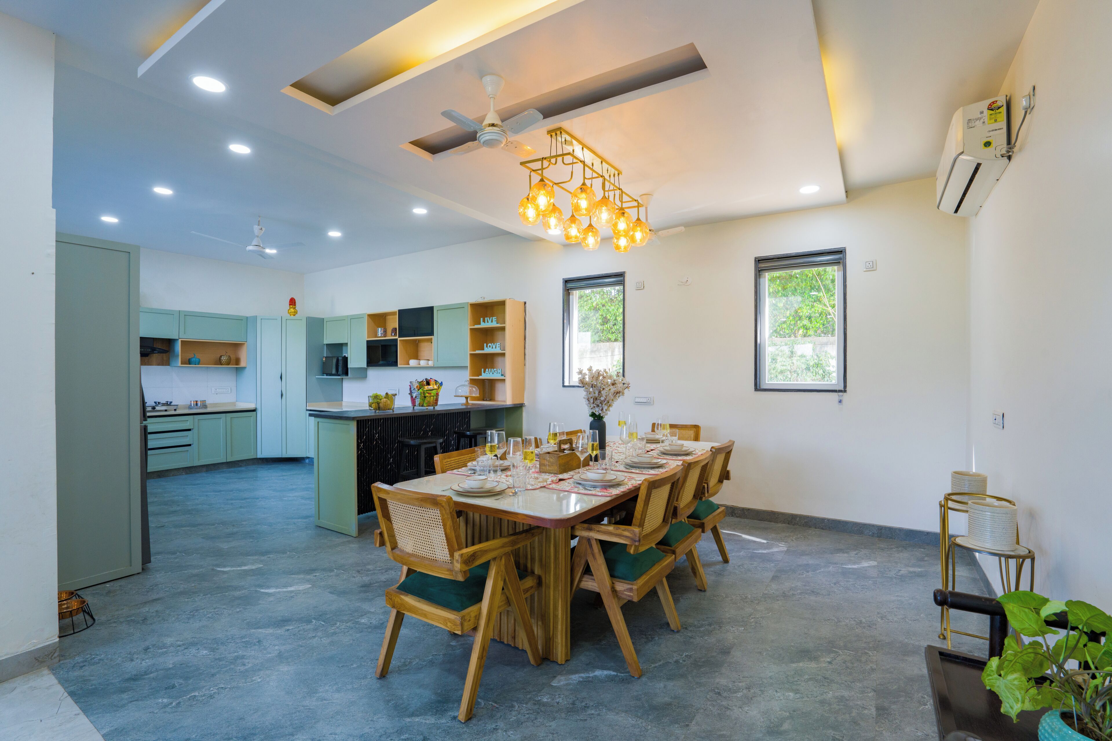 A modern kitchen with built-in appliances, a dining area with a wooden table and chairs, and a ceiling fan.