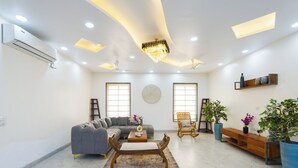 A modern living room with a sectional sofa, a wooden bench, a coffee table, and a chandelier. - ELIVAAS Adhiva Retreat 5 BHK Farmhouse (Gurugram)