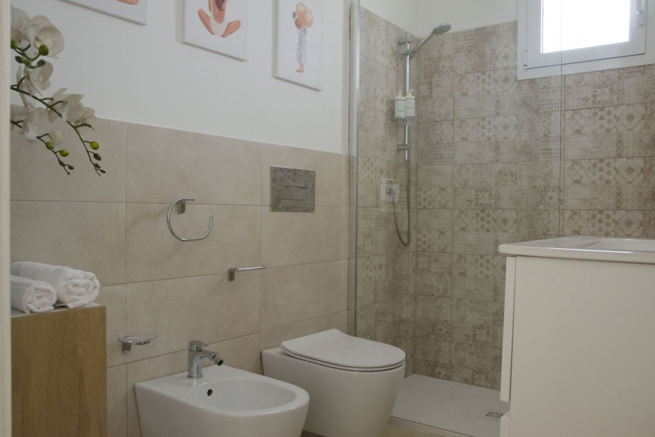 A bathroom with a sink, bidet, toilet, and shower.