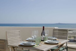 A table set for dining with a view of the sea and a distant island. - Almaré Seafront Apartment with Terrace & Pools  (Pachino)