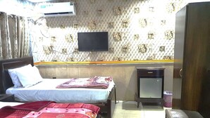 Ein Hotelzimmer mit zwei Betten, einem Fernseher, einem Kleiderschrank und einem kleinen Tisch.