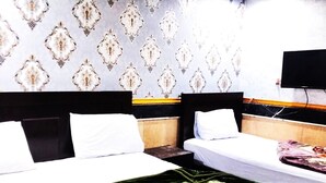 Ein Hotelzimmer mit zwei Betten, einem an der Wand befestigten Fernseher und Wandtapete mit Muster.