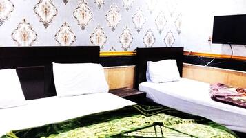 A hotel room with two beds, a television on the wall, and patterned wallpaper.