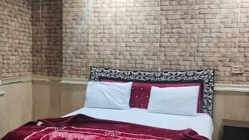A bedroom with a brick-patterned wall, a bed with a floral bedspread, and a ceiling fan.