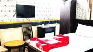 Ein Hotelzimmer mit Bett, Schreibtisch, Stuhl und Fernseher.