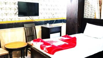 A hotel room with a bed, a desk, a chair, and a television.