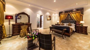 Une chambre spacieuse avec un grand lit, un coin salon avec un canapé et des fauteuils, une table à manger avec des chaises et un miroir décoratif.